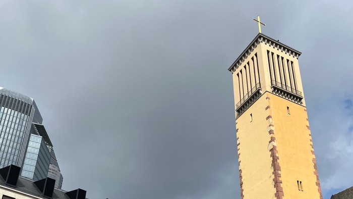 Turm neben modernem Gebäude und Bäumen