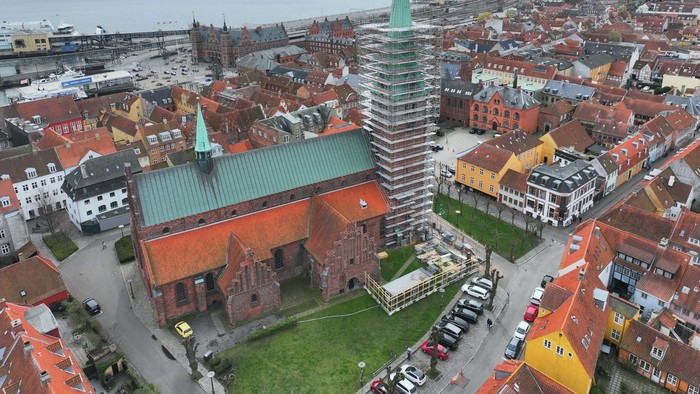 Byen med kirke med højt tårn og røde tag.