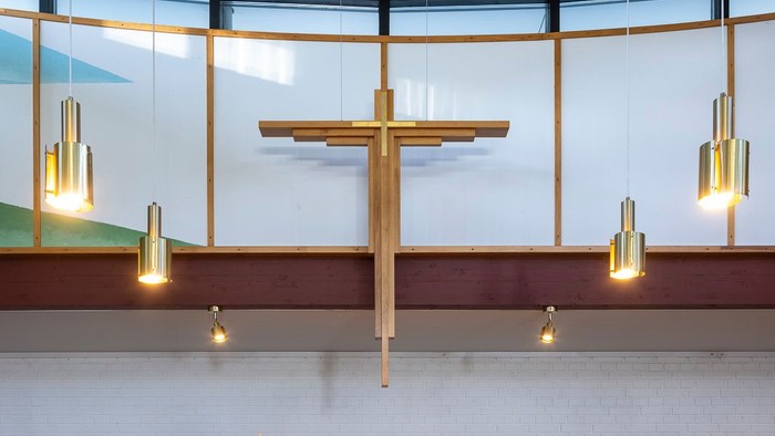 En moderne kirkeinteriør med alter, lys og blomster.