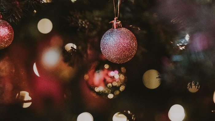 En juletæppe med glitrende pynt og lys.