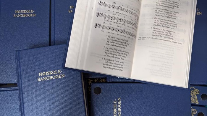 Blå boger med guldtrykket "Højskole-Sangbogen" og noter.