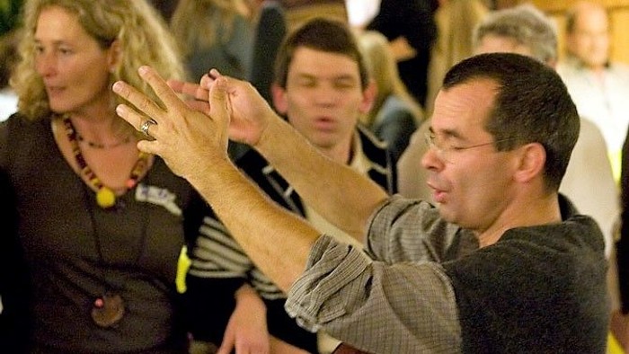 Ein Mann spielt Gitarre und singt in einer Gruppe von Menschen.