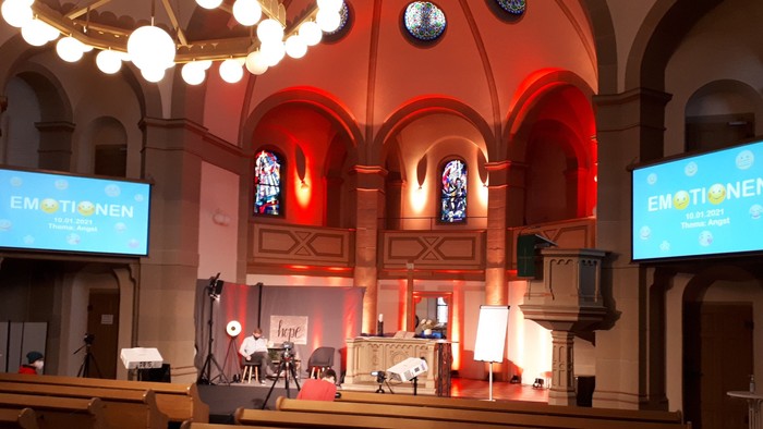 In der Kirche findet eine Veranstaltung mit zwei großen Bildschirmen und Bühne statt.