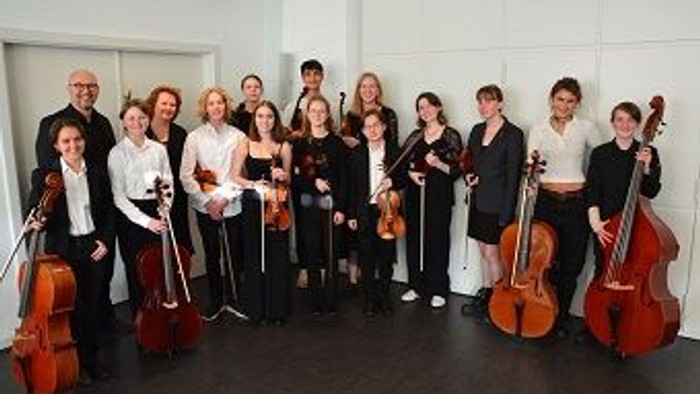 En gruppe musikanere poser med deres celler i en hall