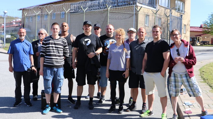 En gruppe unge og voksne står sammen med rollerblader i en park.