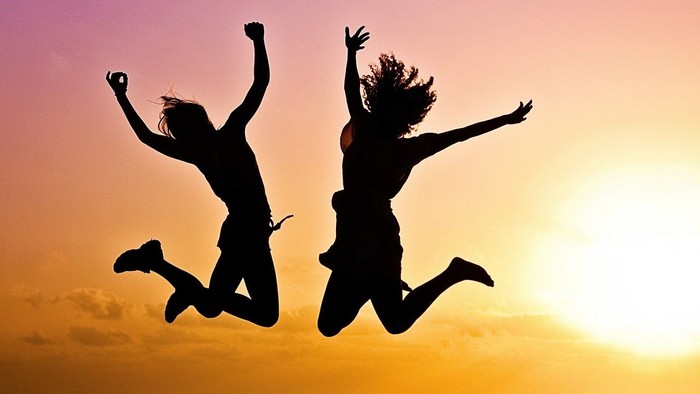 Zwei Personen springen vor Sonnenuntergang in die Luft.