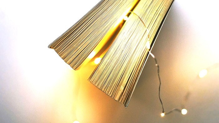 Ein aufgeschlagenes Buch liegt auf einem Bett mit Lichterketten.