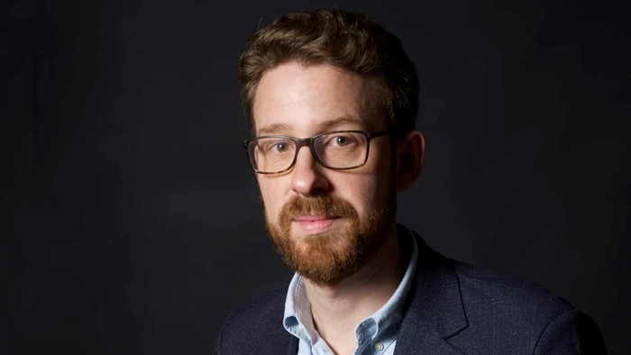 En mand med briller og skæg, der ser alvorligt ud.