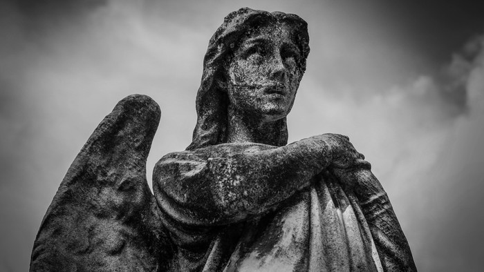 En svart og hvid statue af en engel med udbrede vinger.