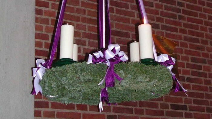 En hængende julekrans med lys og bænder