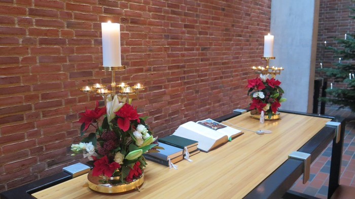 Bord med blomsterarrangementer og lysstake mod rød mursten