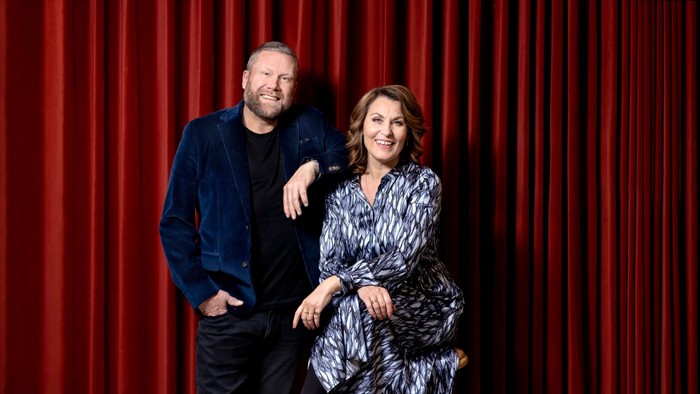 En mand og en kvinde står sammen foran røde teatrepper.