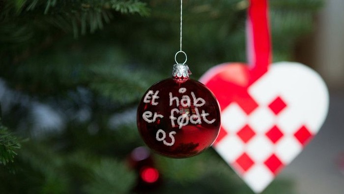 En glædelig julkugle med teksten "et hab er født os" hænger på en juletree