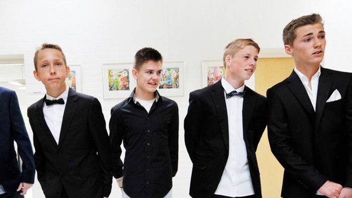 Fire unge mænd i formelt tøj står i en linje.