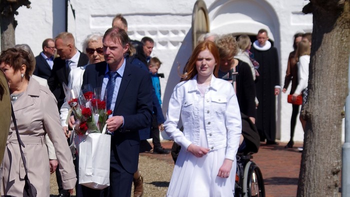 En gruppe af mennesker går forbi et hvide og orange bygning.