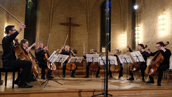 En orkester optræder i en kirke med en dirigent og musikere med strengeinstrumenter
