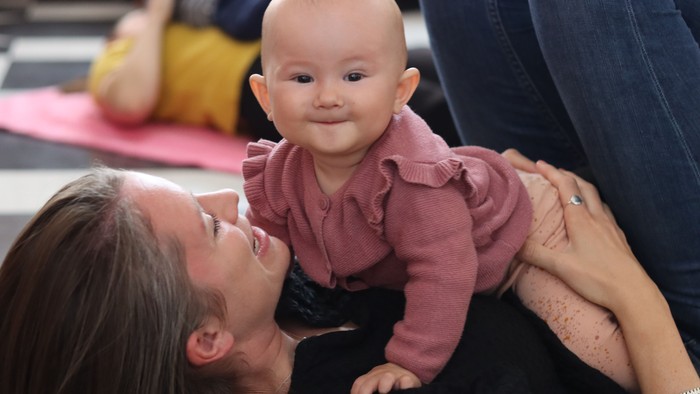En kvinde holder et spæd barn på sin skørt, mens de sidder på en guldug.