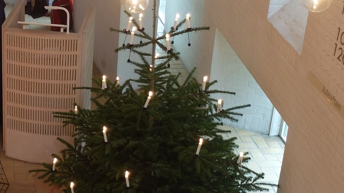 En juletree med lys og pynt i et rum med trappe og møbler