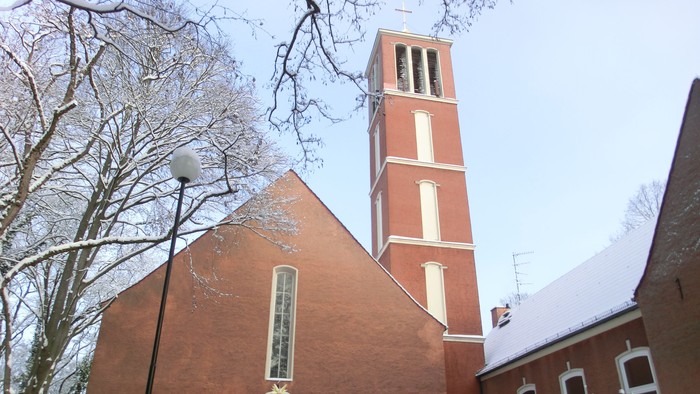 Kirchengebäude aus rotem Backstein mit hohem Turm im Winter