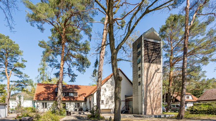 Das Bild zeigt eine Kirche mit hohem Turm und umgeben von Bäumen.
