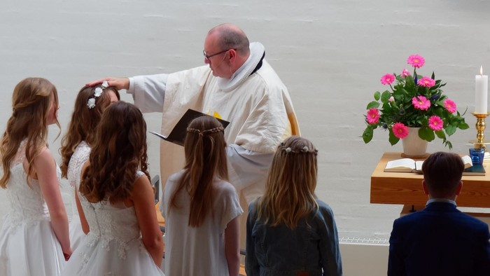 En præst udfører en ritual på et barn, mens andre barn og en voksne kigger til.