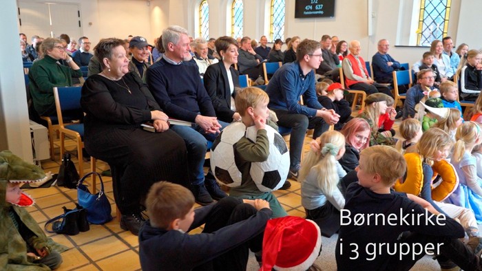 En gruppe børn og voksne samles i en kirke, hvor børnene spiller fodbold.