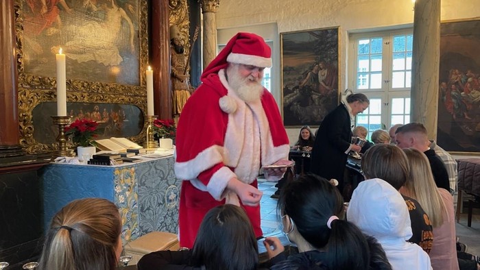 Santa Klaus giver barnene julegaver i et historisk rum