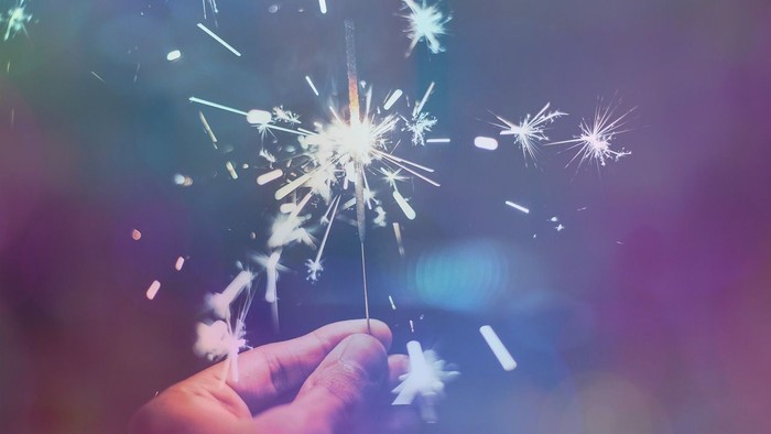 En hånd holder en sparkelende bengel med lysende stjerner.