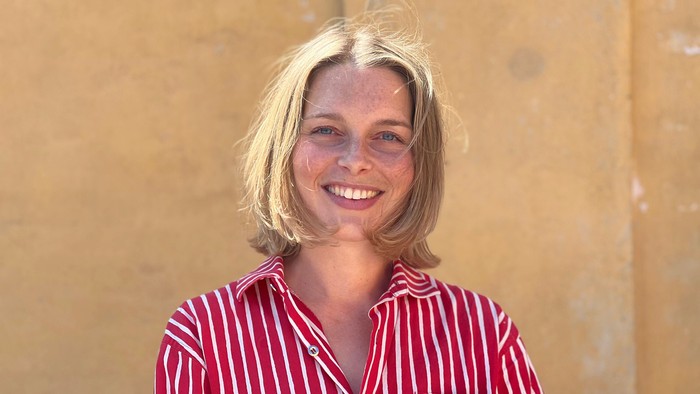 En kvinde med blond hår smiler til kameraet.