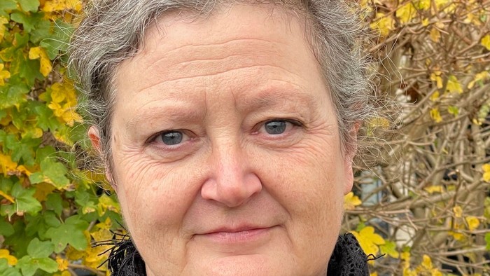 En kvinde med kort grå hår og sort skærm around halsen.