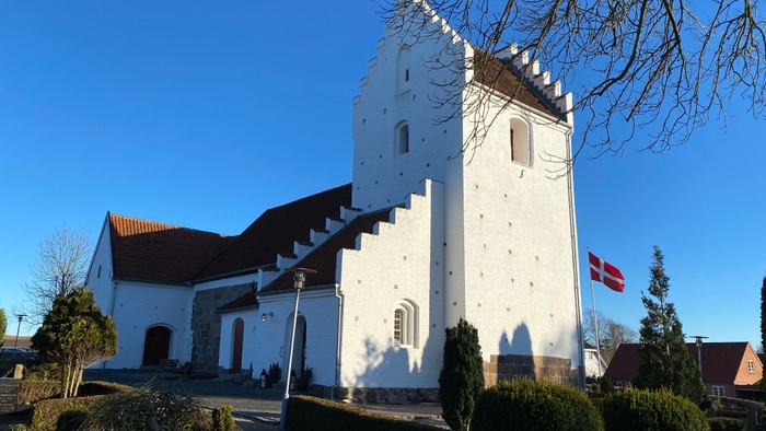 Hvid kirke med tårn og dansk flag.