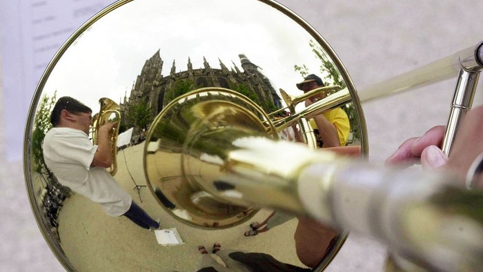 Ein Mann spielt ein Blechblasinstrument und schaut in einen Spiegel.