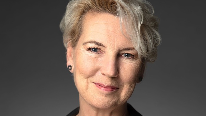 En kvinde med kort, blond hår og en sort jakke.