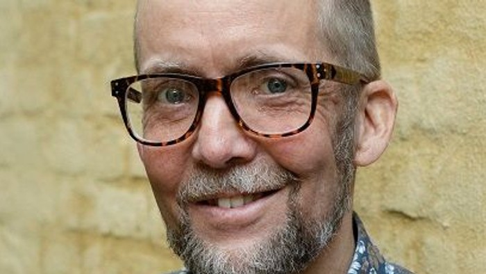 Mand med briller og kort hår, smiler til kameraet.