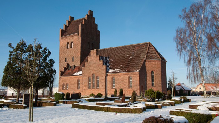 Røde kirke med tårn og snede på jorden