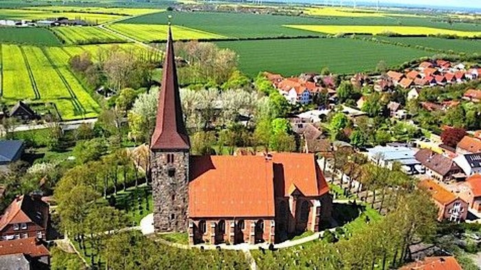 Ein Dorf mit einer Kirche und umgebenden grünen Feldern