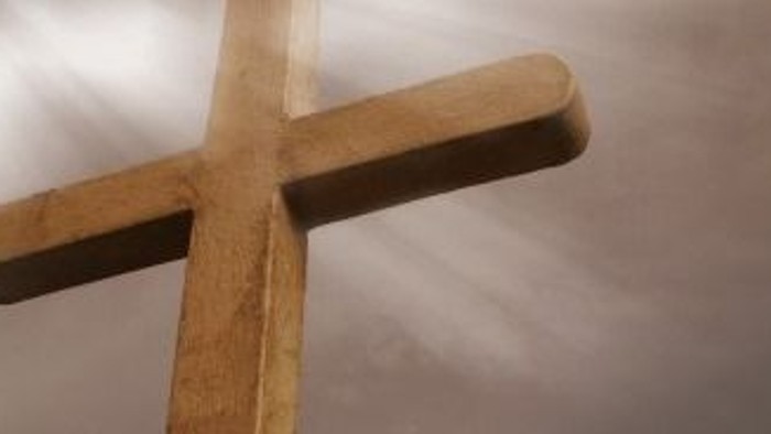 Et stort, tømret kors mod en skyerne himmel.