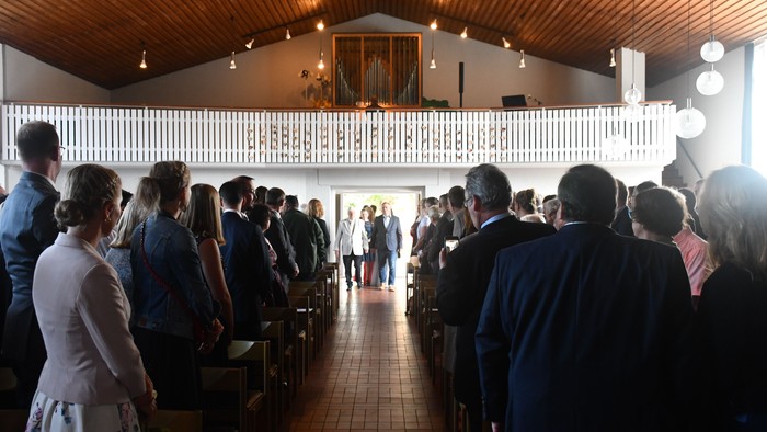 Eine Hochzeitsgesellschaft in einer Kirche, Gäste stehen und sitzen.