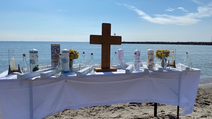 Ein Tisch mit Kreuz und Blumen am Strand