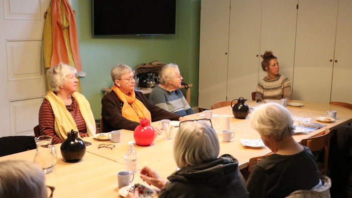 En gruppe ældre personer sidder ved et bord og spiser.