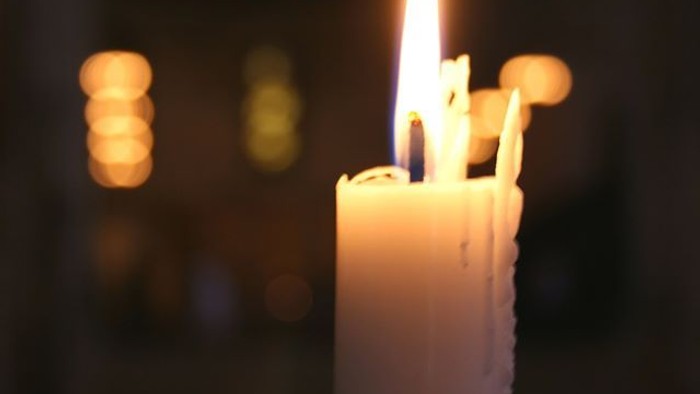 En lysende lysestøbe med smeltet top og baggrund af andre lys.