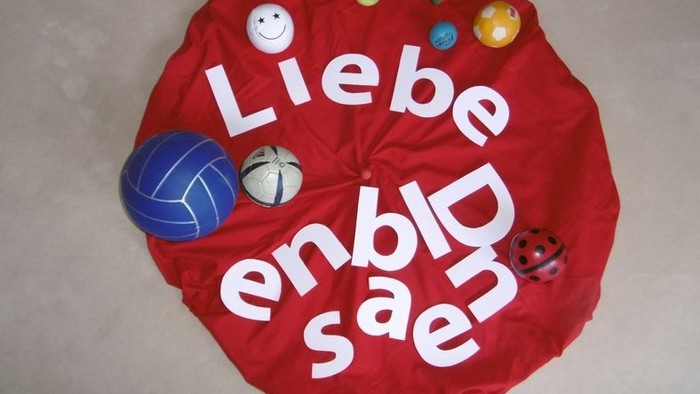 Ein roter Kreis mit weißen Buchstaben und verschiedenen Spielbällen darauf