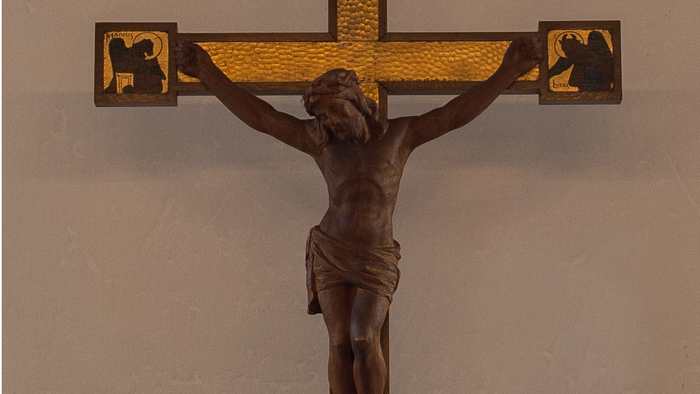 Krucifikset med Jesus på korset er monteret på en rosa væg