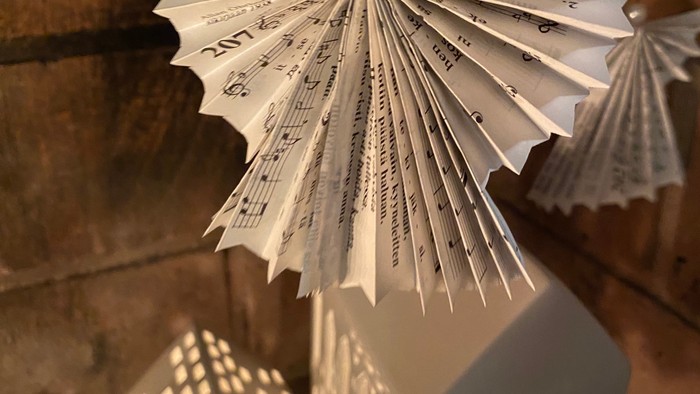 Ein Engel aus Papier schwebt über zwei beleuchteten weißen Häuschen.