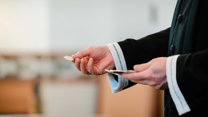 En person i mørkt tøj holder en lille papirflæske og en pen.