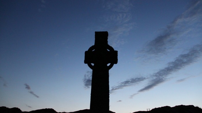 En stor, mørk korsformet struktur mod en blå himmel med få skyer.