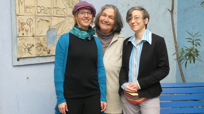 Drei Frauen stehen vor einer blauen Wand mit einem Schild "Meerdaunhaus".