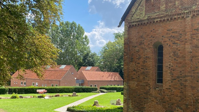 En trækirke med røde tag og en mur af røde mursten med et vindue