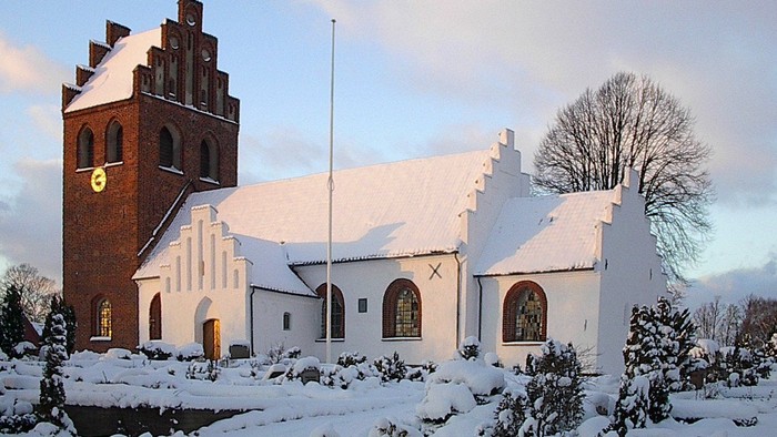 En snede kirke med tårn og klokke.