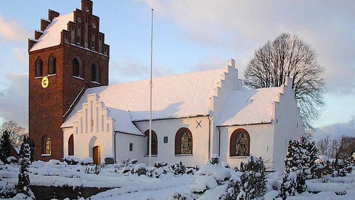 En snede kirke med tårn og klokke.